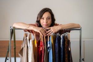 Femme appuyée sur un portant rempli de vêtements
